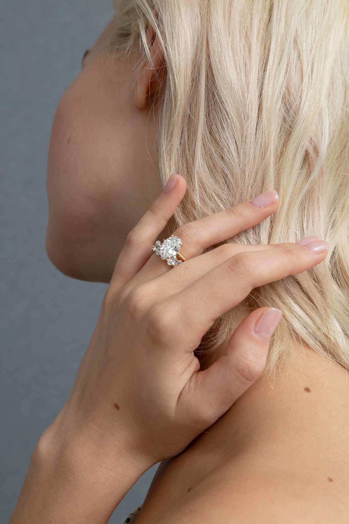 A model wears a custom 3 carat oval engagement ring with the Sans Cesse Oval Eternity band - both in 18K Yellow Gold. The diamonds are D color, IF/VVS diamonds.