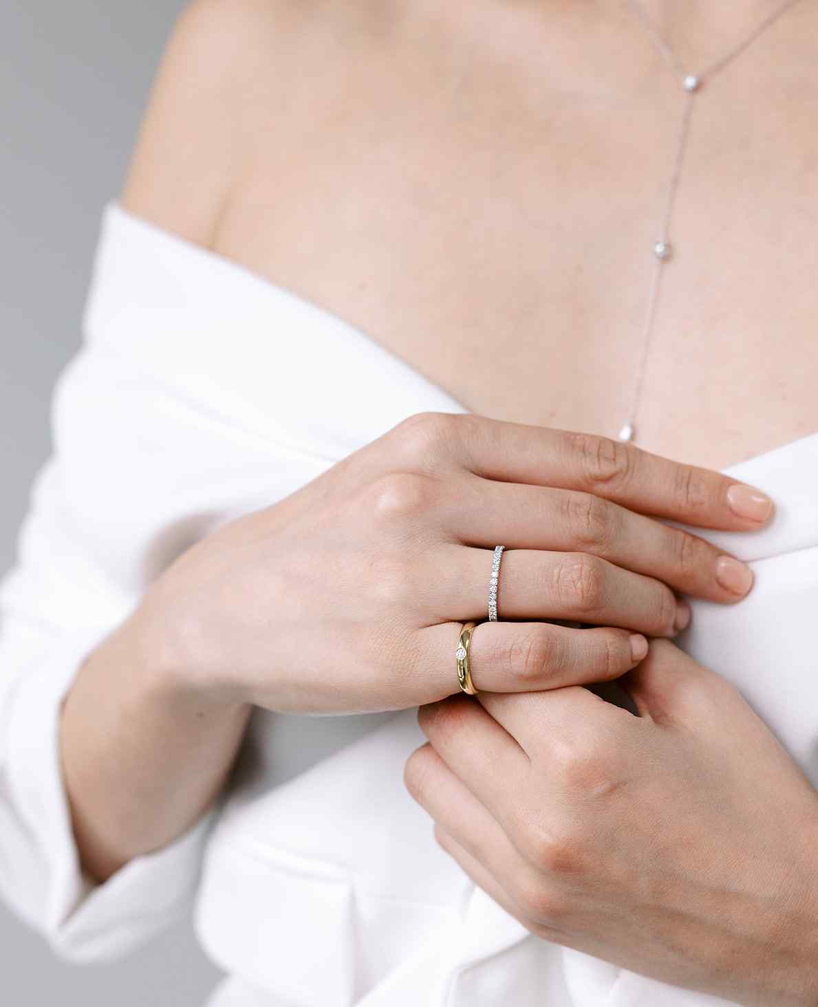 A model wears the Éternité ring and the Talia Pinky ring - both of which can be used as a wedding band. Made with lab-grown diamonds and recycled 18K gold.