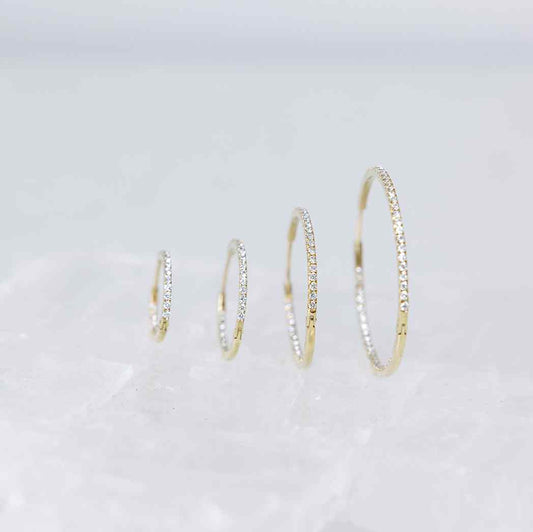 Diamond hoops with round brilliants lining the interior and exterior for ultimate sparkle. They come in four different diameters shown here -- 12, 16, 22, and 30mm. Meant for stacking in any combination - shown in Yellow Gold here.