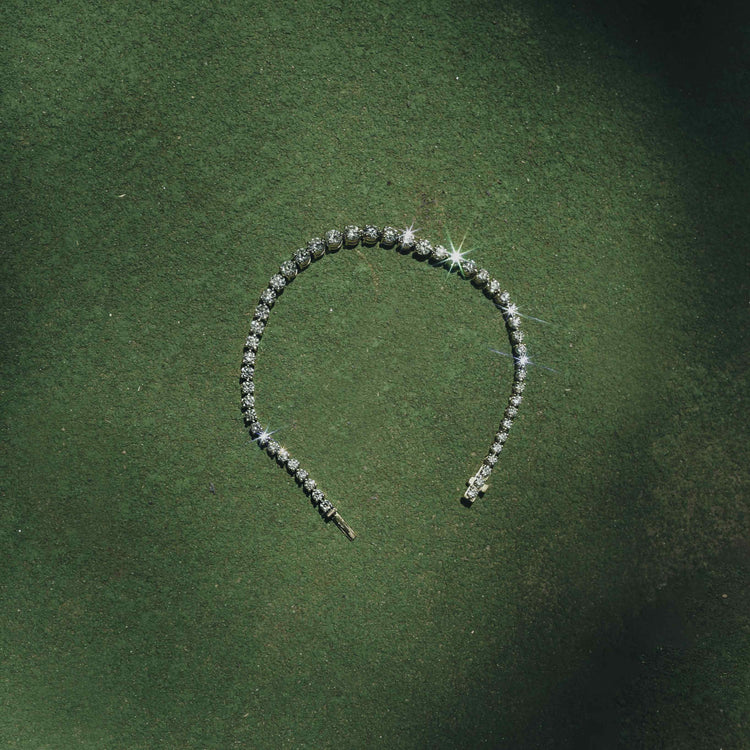This graduated tennis bracelet features round brilliants in a three-prong solitaire setting of 18K Yellow Gold. 6 total carat weight, with a center stone carat weight of 0.25, each diamond is hand-set in an open basket setting to allow maximum light play on the D color, IF/VVS clarity diamonds.