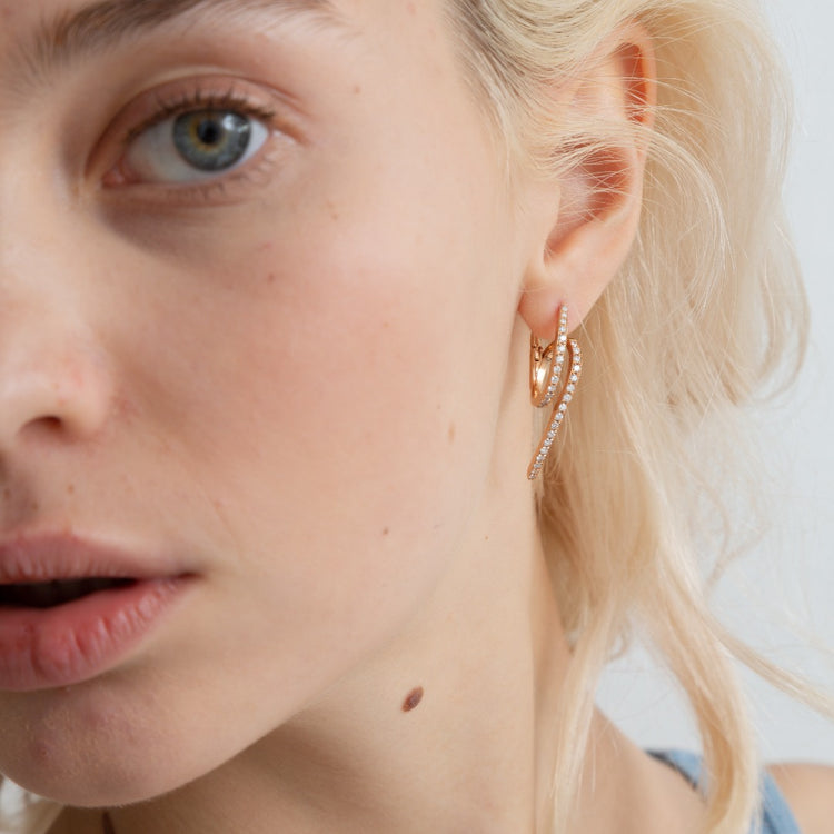 A model wears the Lucia earrings - made of pavé diamonds - which sparkle brilliantly in the sun. The twist earrings are delicate and seem to dance with movement.