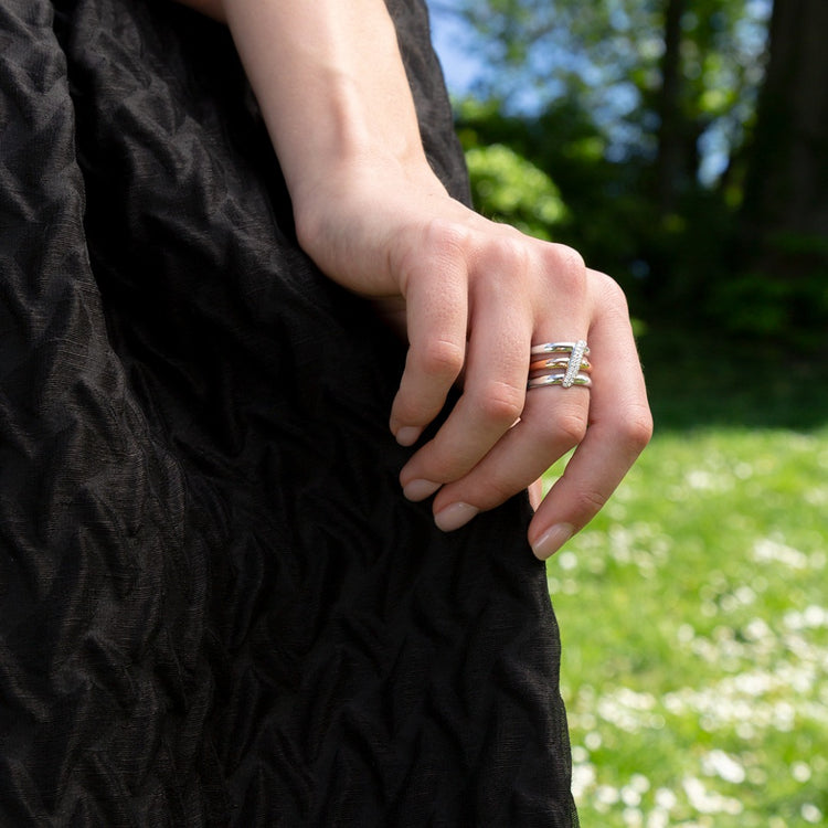 A model wears the Dalliance Sash Ring - made with recycled 18K White and Rose Gold - mixing cool and warm tones for the perfect statement ring. The sash of pavé diamonds are all D color, IF/VVS clarity.