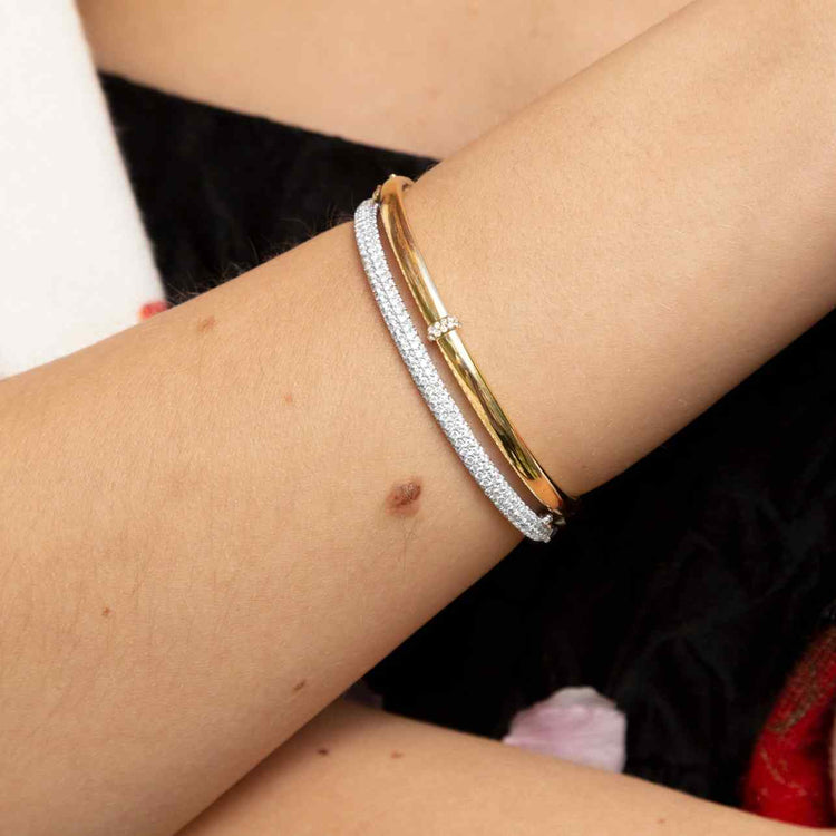 A delicate band of diamonds encircles one point (in the middle) along a 24-gram gold bangle. Shown here paired with the Dalliance Pavé bracelet for a brilliant stack. Our Dalliance Gold bracelet has an inner circumference of 6.3" (16 cm) with a long axis of 2.2" (5.6 cm) and a short axis of 1.8" (4.6 cm). 18k recycled yellow gold shown here.