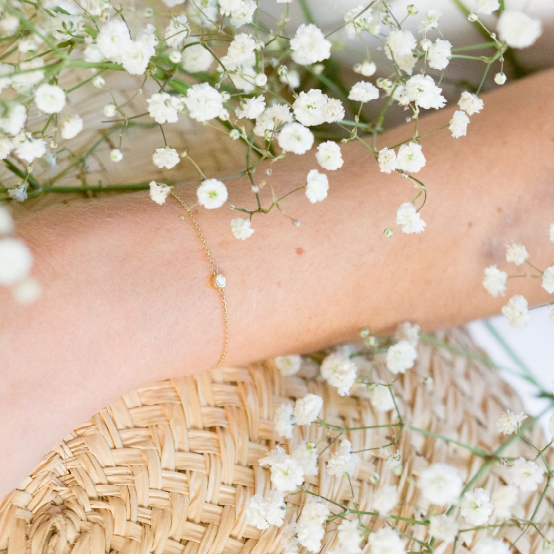 A model wears this delicate bracelet - which features a solitaire 0.1 carat round brilliant bezel set in 18k recycled gold. This bracelet can be adjusted to two different lengths, 6.3" (16 cm) and 6.7" (17 cm). Reach out to our team for further customization options. Shown here in Yellow Gold.