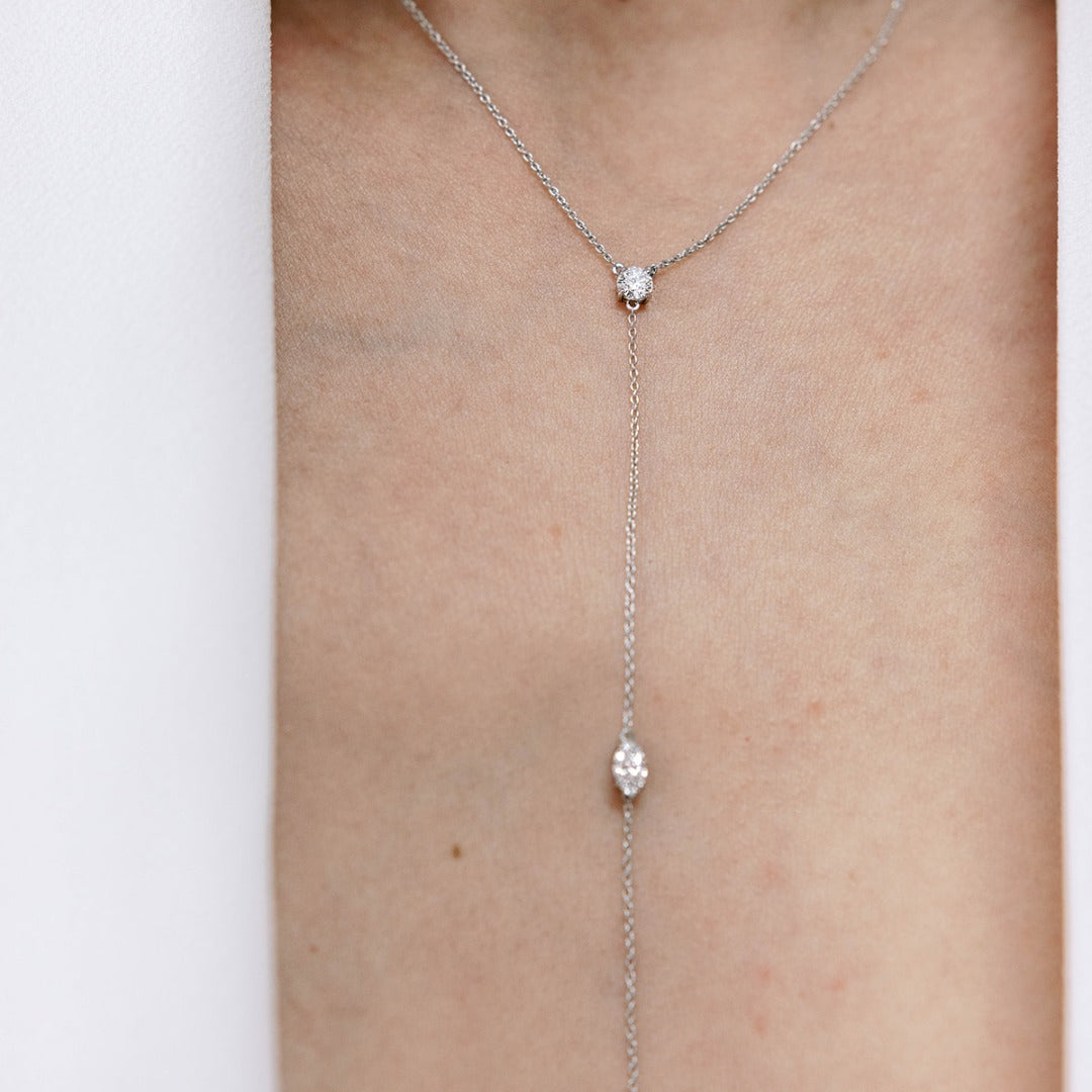 Three 0.25ct diamonds are strung along a 18k gold chain. Diamond shapes from top to bottom are: Round, Marquise, Pear. This photo shows the top two diamonds. The collar of the necklace measures 16 inches (40cm); the length of the drop is 4 inches (10cm). To customize, please write to our Atelier. 18k White Gold shown here. Pair with the matching earrings in the Lariat collection.