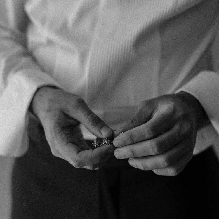 A model holds the Boutons de Manchette, or Cufflinks, which feature 23 grams of solid 18K Yellow Gold, hand-cast to emulate the birch trees of Belgium. Perfect as a men's wedding gift.