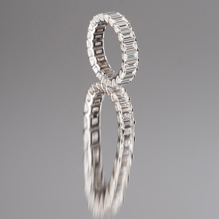 In this emerald diamond eternity band, D color Emerald diamonds are set precisely to radiate light from their infinite hall of mirrors. Size and color are fully customizable. 7 total carat weight shown here in 18K White Gold and Palladium.