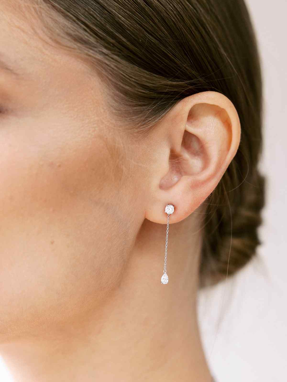 Diamond shapes - A round diamond scintillates from 57 facets. This shape is as timeless as it is brilliant. A model wears the Lariat Deux drop earrings - featuring a round brilliant at the stud.
