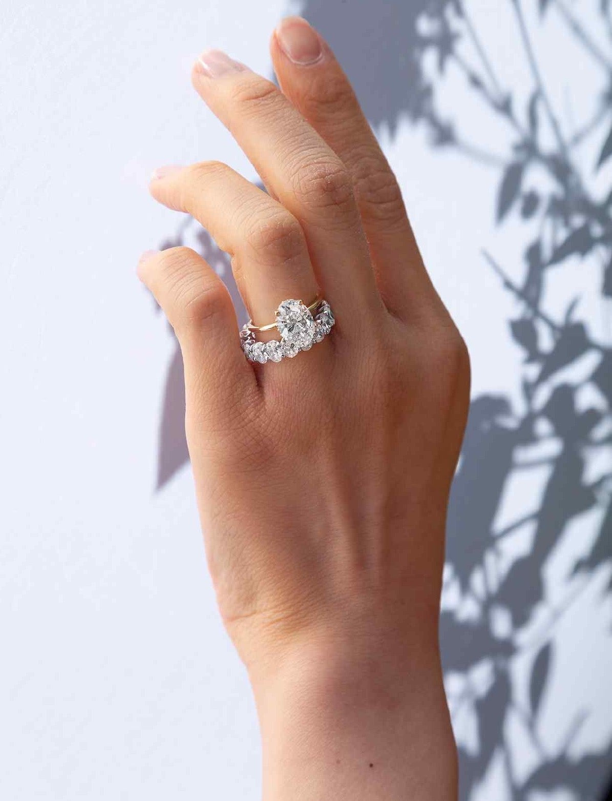 A model wears a custom 3 carat oval engagement ring with the Sans Cesse Oval Eternity band - both in 18K Yellow Gold. The diamonds are D color, IF/VVS diamonds.