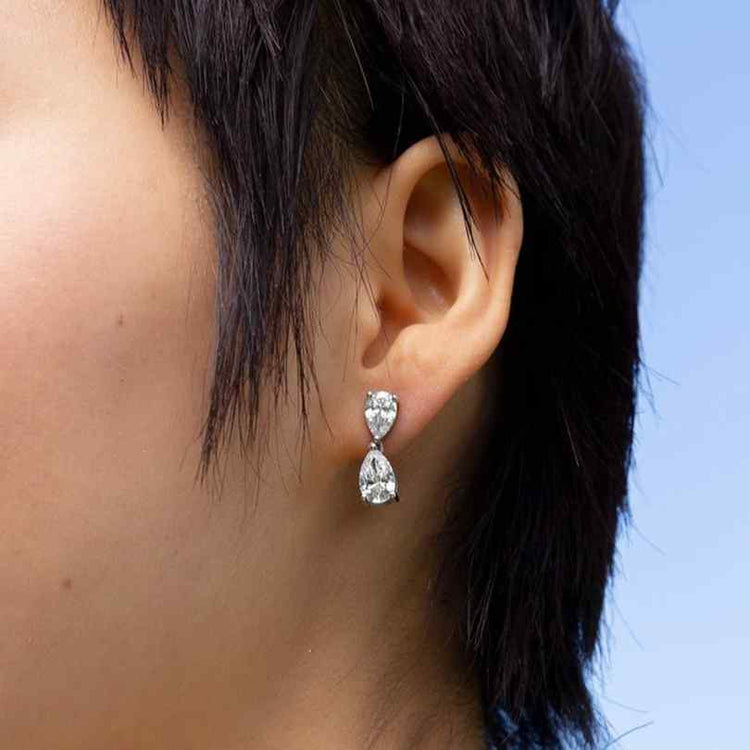 A model wears the stunning Bisous de Poires earrings - with pear-shaped diamonds that drop delicately from the ear in White Gold.