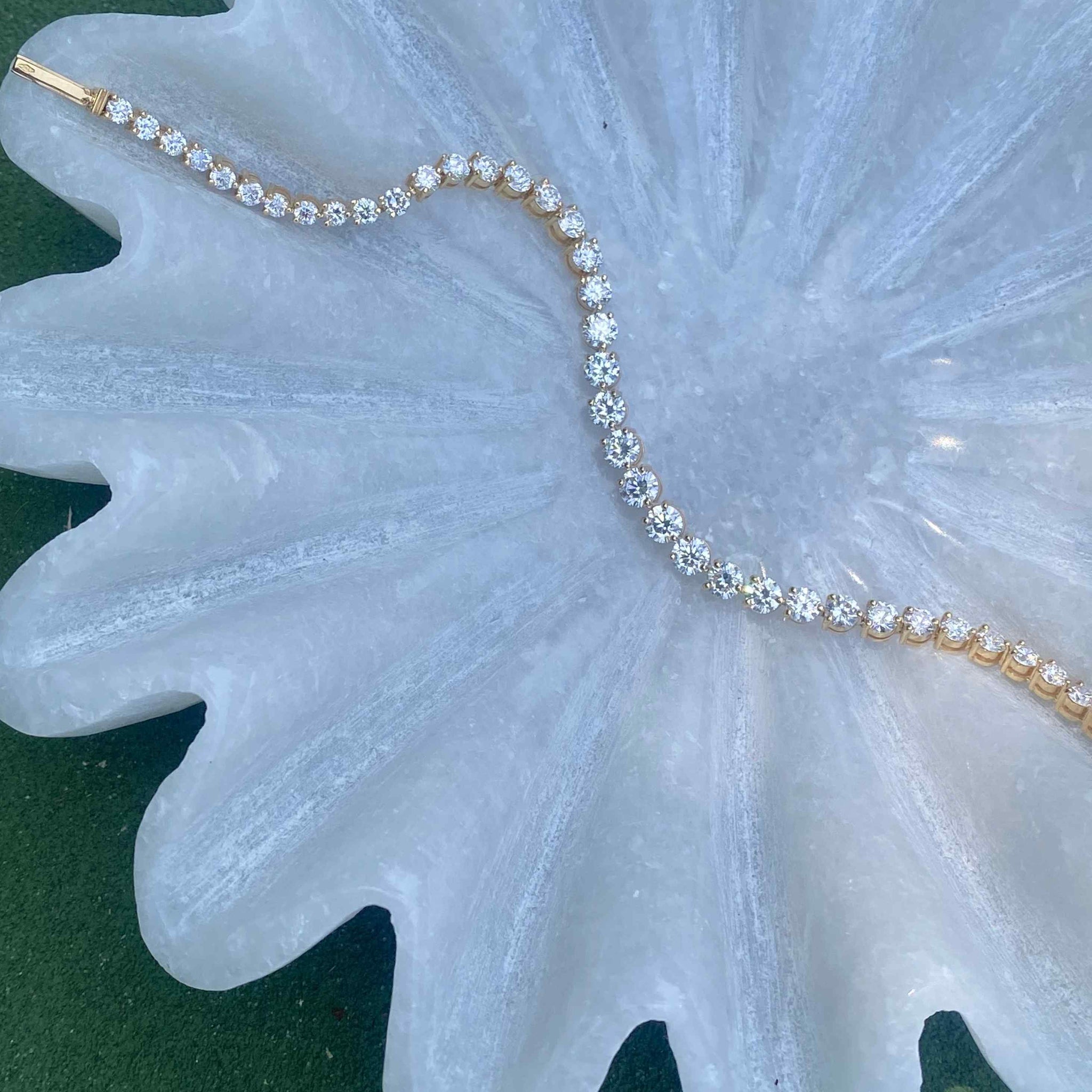 This graduated tennis bracelet features round brilliants in a three-prong solitaire setting of 18K Yellow Gold. 6 total carat weight, with a center stone carat weight of 0.25, each diamond is hand-set in an open basket setting to allow maximum light play on the D color, IF/VVS clarity diamonds.
