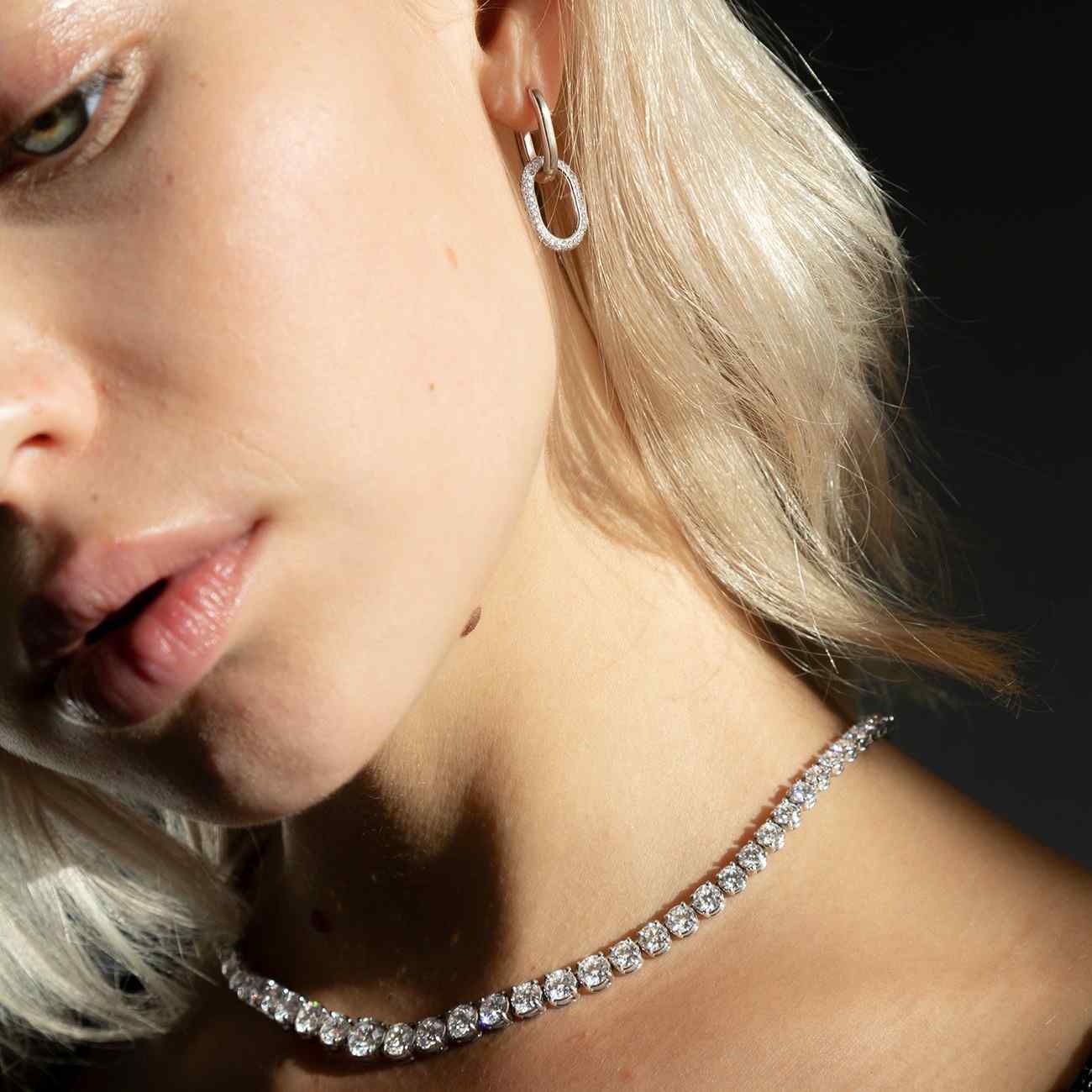A model wears the Collier Rivière Tennis Necklace paired with the Dalliance Ecluse Earrings as an evening look. This 25ct graduated diamond tennis necklace features flawless round brilliants in a four prong solitaire setting. D-color, IF/VVS diamonds crescendo toward a center diamond of 1ct. The length of this striking piece is 16 inches (40cm).