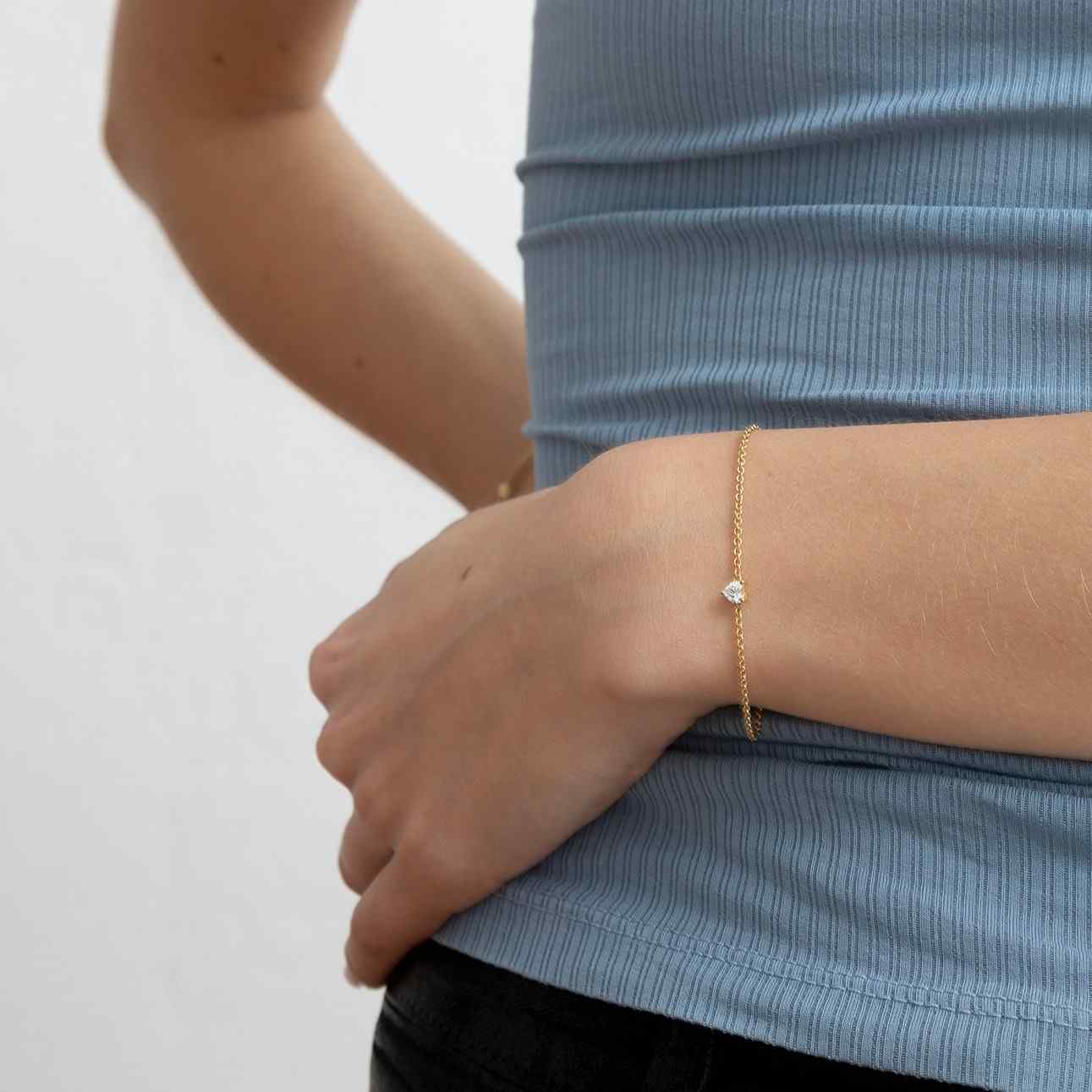 A model wears the Coup de Cœur bracelet on an 18K gold chain. The bracelet features a brilliant heart diamond in the center of the gold chain. This diamond bracelet can be adjusted to two different lengths, 6.3" (16 cm) and 6.7" (17 cm).
