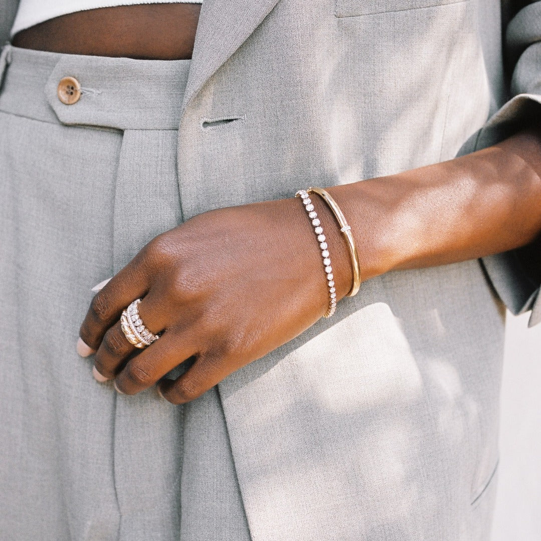 A model wears the Dalliance Gold Bangle paired with the Bracelet George Rivière Tennis Bracelet for the perfect bracelet stack. The diamonds in the Tennis Bracelet pair perfectly with the thin strip of diamonds on the gold bangle. Also shown here with our favorite Yellow Gold ring stack - the Sans Cesse Pear Eternity, Dalliance Pavé Ring, and Lune Ring.