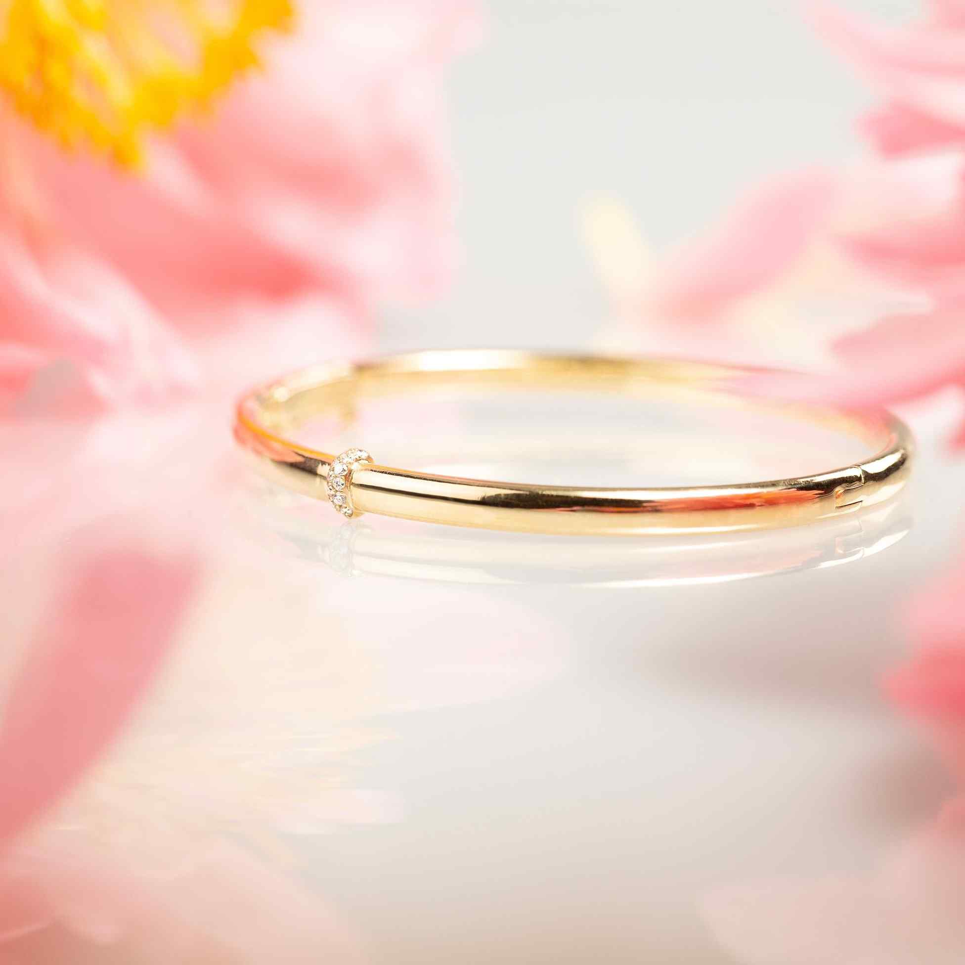 A delicate band of diamonds encircles one point along a 24-gram gold bangle. Our Dalliance Gold bracelet has an inner circumference of 6.3" (16 cm) with a long axis of 2.2" (5.6 cm) and a short axis of 1.8" (4.6 cm). 18k recycled yellow gold shown here. Please reach out to our Atelier to customize the size of the bracelet.