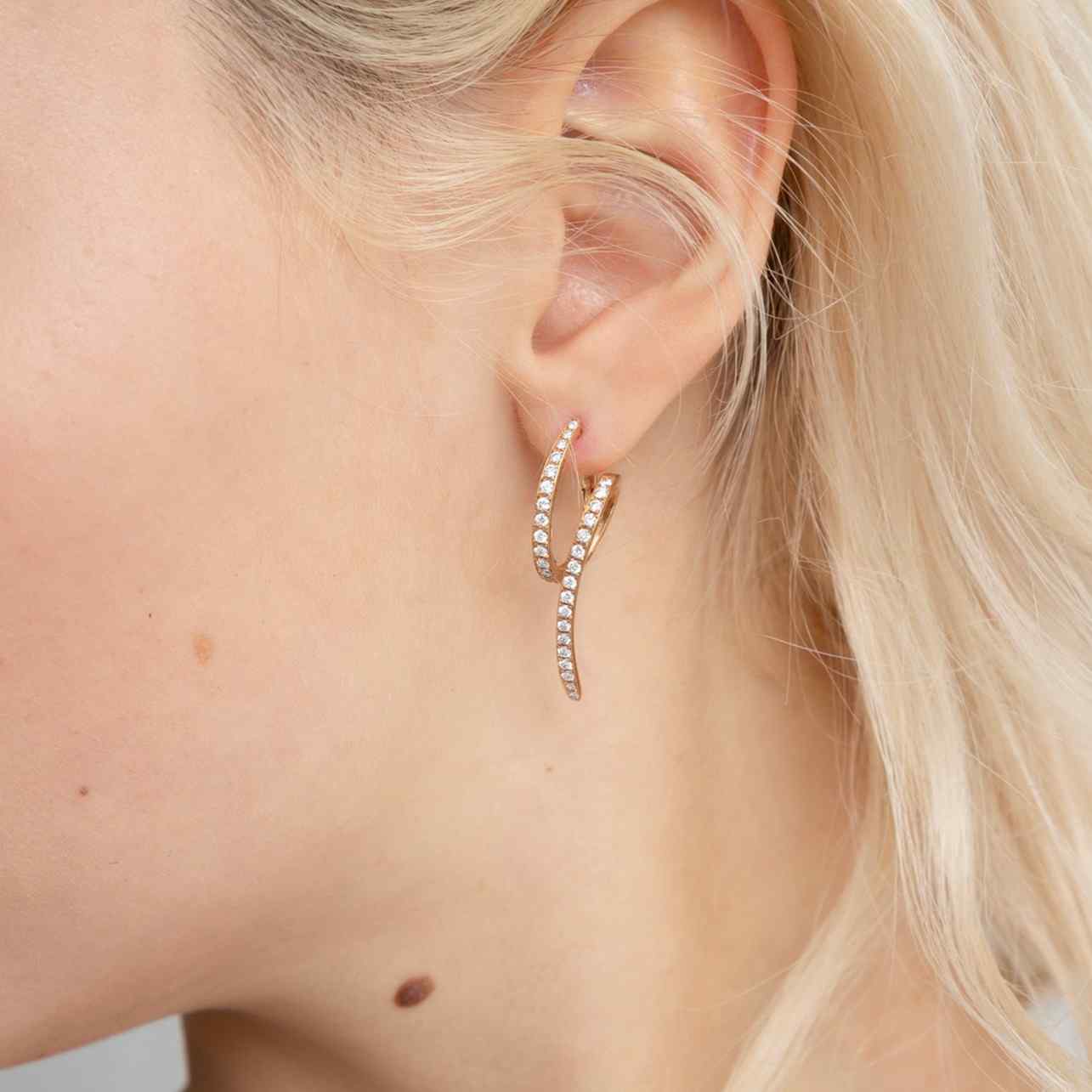 A model wears the Dalliance Lucia Earrings - a unique piece featuring 62 diamonds in a twist design with 6.25 grams of 18k recycled gold. Sold as a pair. Shown here in 18K Rose Gold.