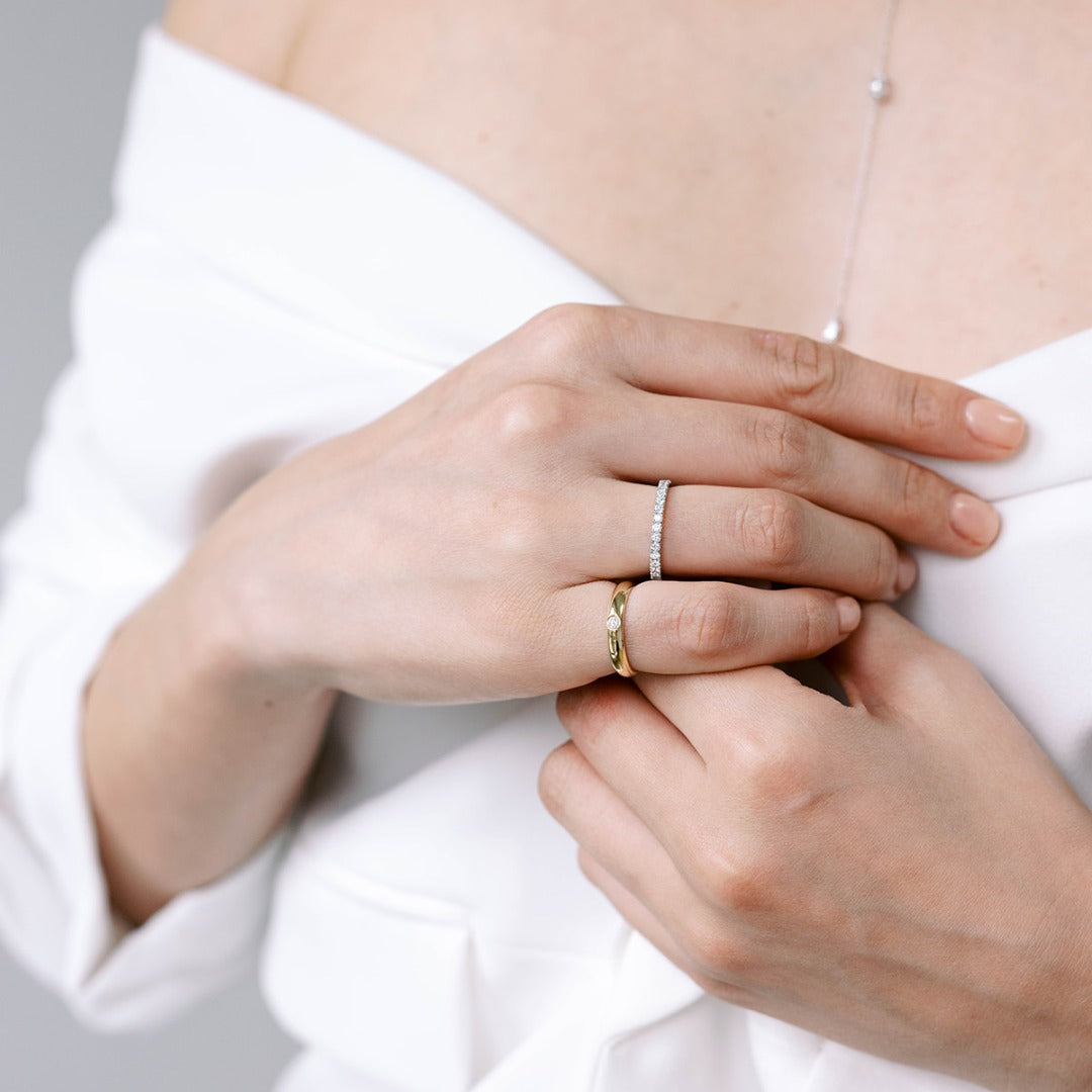 A model wears the Éternité ring on her ring finger paired with the Talia Pinky Ring. D color, IF/VVS clarity round brilliants held in 2.55 grams of recycled 18k gold for a timeless pavé diamond eternity band totaling ~0.8ct.
