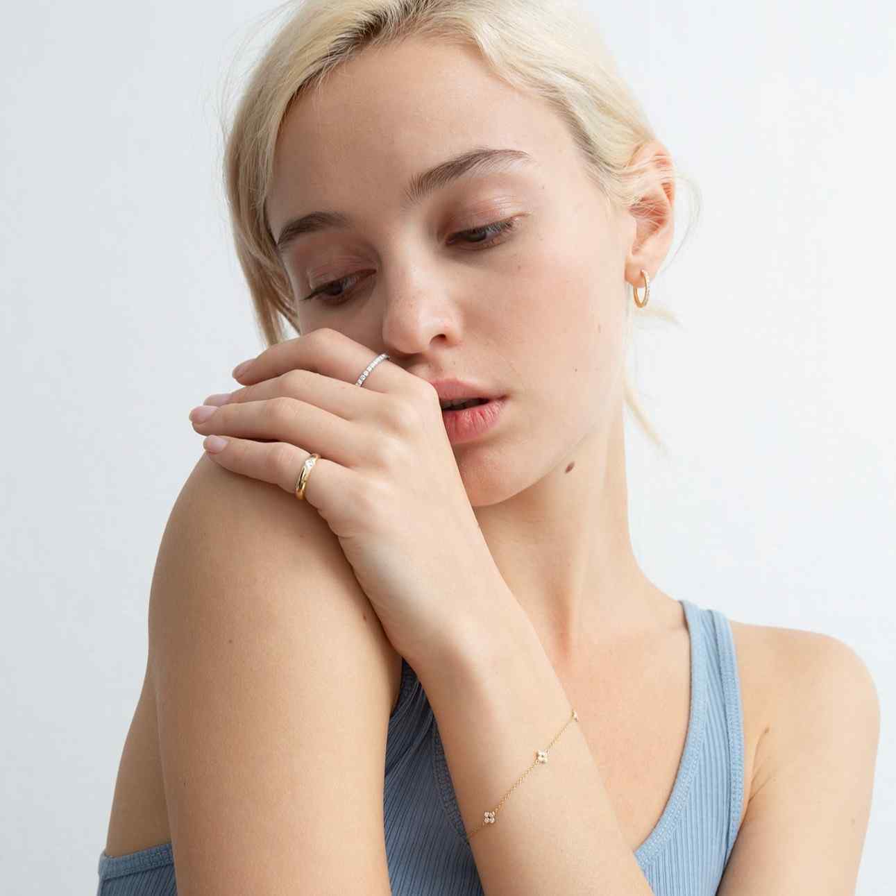 A model wears the Éternité ring on her pointer finger paired with the Talia Pinky Ring. Also paired with the Toujours earrings and Fleurs Éparpillées bracelet. D color, IF/VVS clarity round brilliants held in 2.55 grams of recycled 18k gold for a timeless pavé diamond eternity band totaling ~0.8ct.