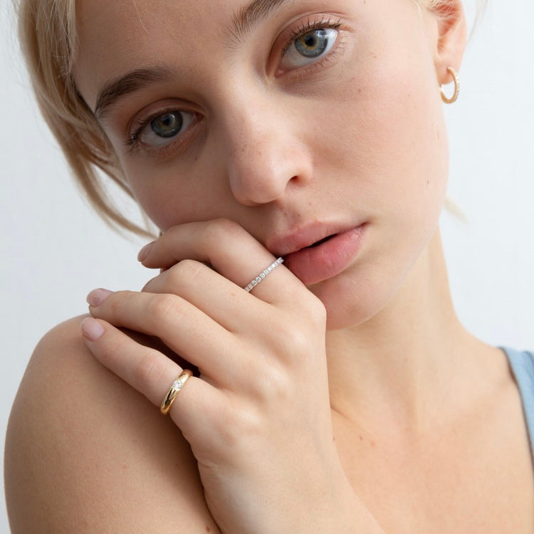 A model wears the Éternité ring on her pointer finger paired with the Talia Pinky Ring. D color, IF/VVS clarity round brilliants held in 2.55 grams of recycled 18k gold for a timeless pavé diamond eternity band totaling ~0.8ct.