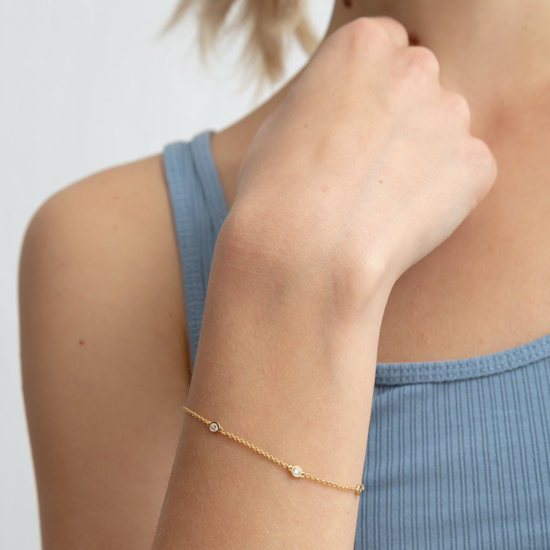 A model wears this delicate bracelet, which features five bezel-set round brilliants totaling 0.25ct. The diamonds sit in a gold chain of recycled 18K gold. This bracelet can be adjusted to two different lengths, 6.3" (16 cm) and 6.7" (17 cm).