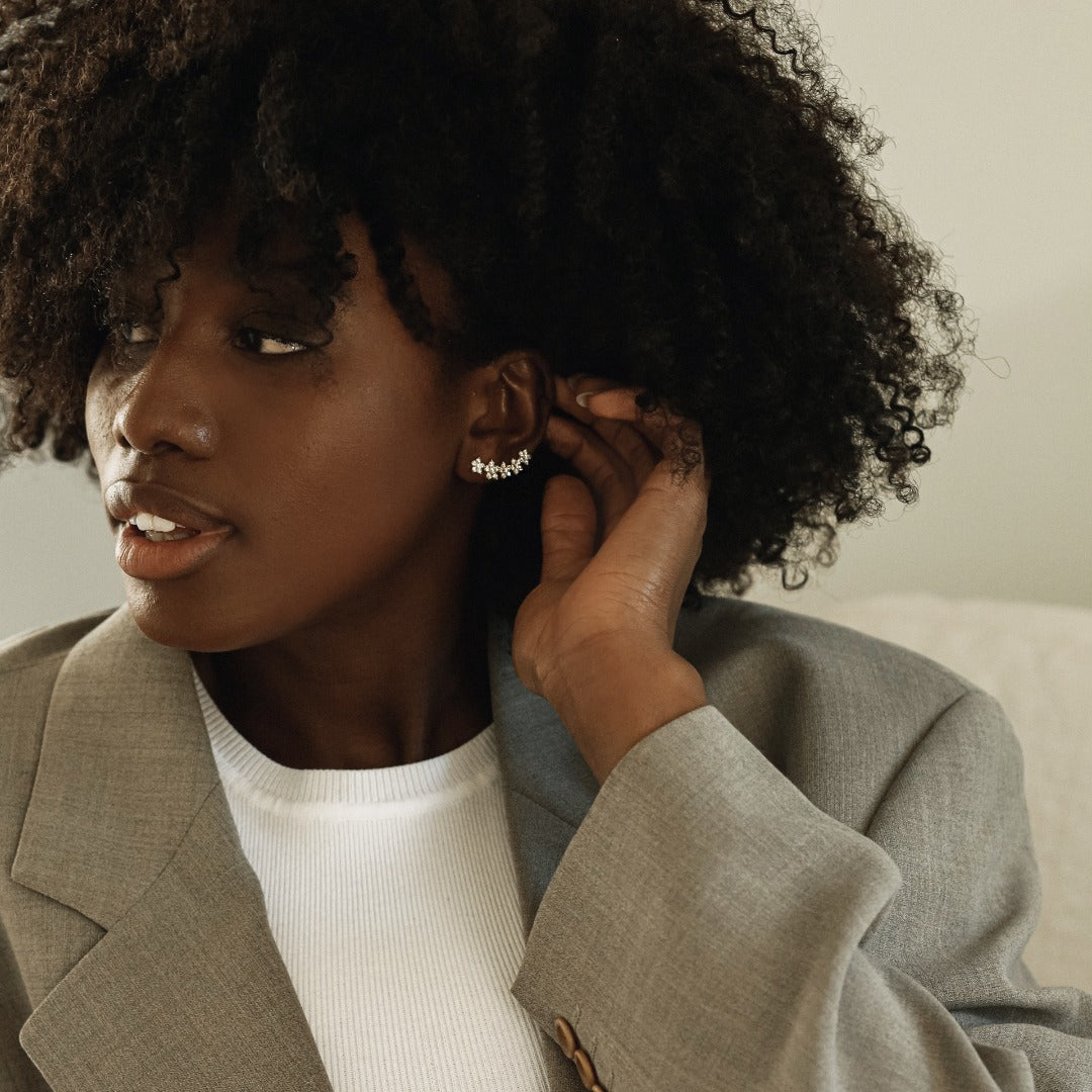 A model wears the playful Fleurs Sur L’oreille earrings with a casual suit - the perfect addition to a classic outfit. The earrings feature 6.4 grams of illustrious 18k gold. The earrings construct a floral garland of 2.2 total carat weight of diamonds. Sold as a pair.