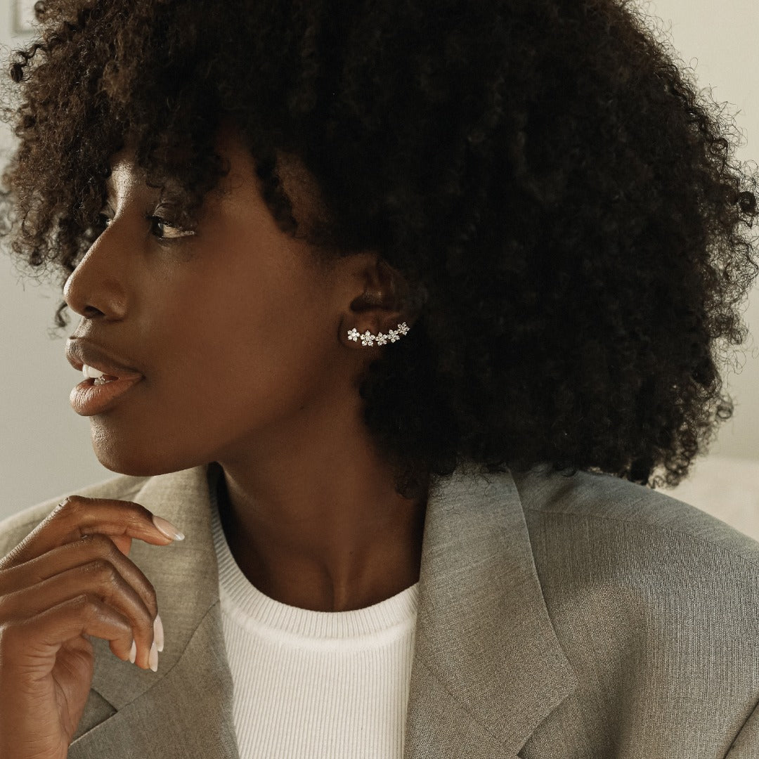 A model wears the playful Fleurs Sur L’oreille earrings with a casual suit - the perfect addition to a classic outfit. The earrings feature 6.4 grams of illustrious 18k gold. The earrings construct a floral garland of 2.2 total carat weight of diamonds. Sold as a pair.