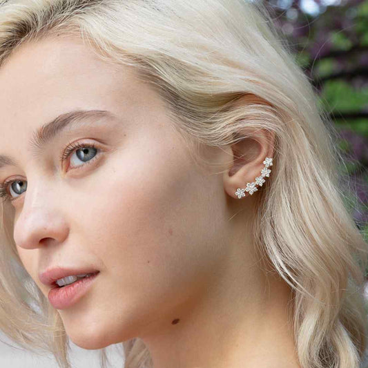 A model wears the feminine Fleurs Sur L’oreille earrings feature 6.4 grams of illustrious 18k gold. The earrings construct a floral garland of 2.2 total carat weight of diamonds. Sold as a pair.