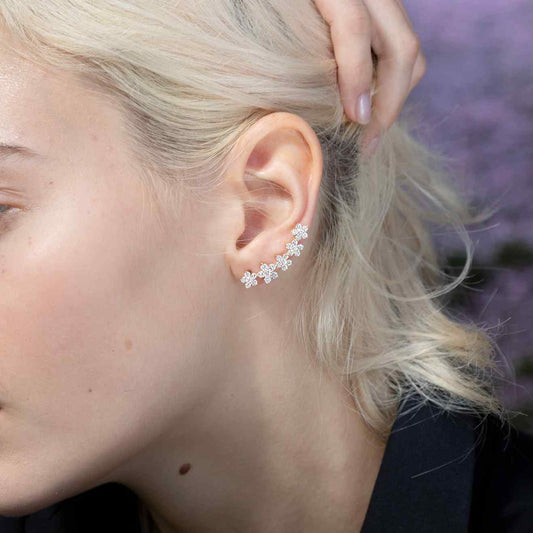 A model wears the graceful Fleurs Sur L’oreille earrings, which feature 6.4 grams of illustrious 18k gold. The earrings construct a floral garland of 2.2 total carat weight of diamonds. Sold as a pair.