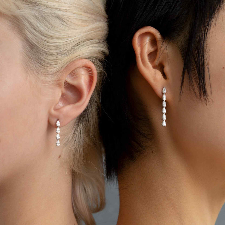 Two models wear the Île Column Earrings - both the Grande and Petite, separately. Whether worn alone, or stacked on the same ear, these earrings shine with D color, IF/VVS clarity diamonds.