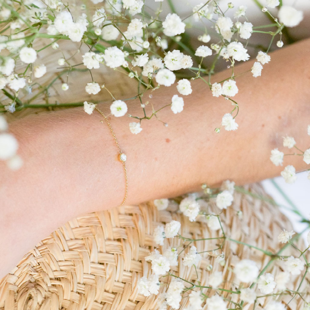 A model wears this delicate bracelet - which features a solitaire 0.1 carat round brilliant bezel set in 18k recycled gold. This bracelet can be adjusted to two different lengths, 6.3" (16 cm) and 6.7" (17 cm). Reach out to our team for further customization options.  Shown here in Yellow Gold.