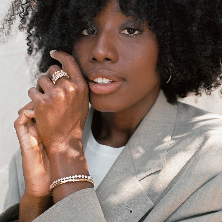 A model wears an unrivaled stack of three rings. The Lune ring was designed to stack with the Dalliance Pavé Ring and Sans Cesse Pear Eternity for a perfect warm gold pairing. The Lune ring features 6 grams of voluminous 18K Yellow Gold with diamonds woven throughout. All diamonds are D color, IF/VVS clarity.