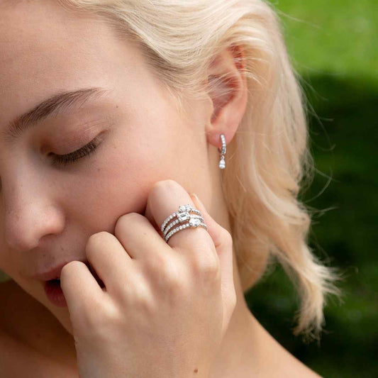 A model wears the Paire de Poires drop earrings with the Trois Pierres ring set. The Paire de Poires earrings feature a 0.15 carat D color, IF/VVS clarity pear diamond that dances at the bottom of an 8mm drop huggie. Sold as a pair, totaling 0.52 carat and 2.36 grams of 18k recycled gold.