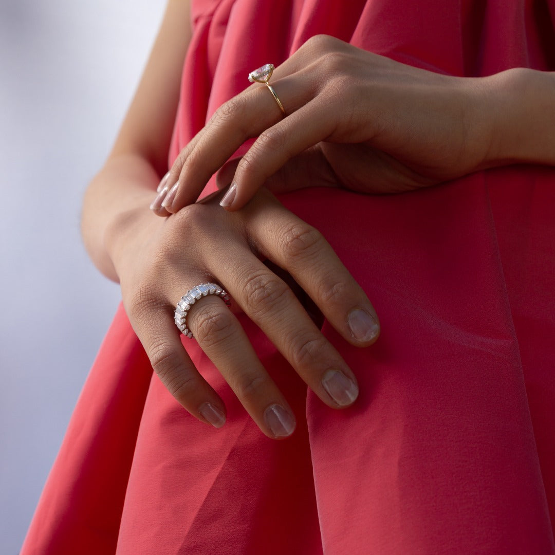 A model wears the Sans Cesse Emerald Eternity, in 18K White Gold and 7 total carat weight size, with a custom Oval Engagement Ring. The Emerald eternity sits on the opposite hand - letting the diamonds breathe. The diamonds are D color, IF/VVS clarity.