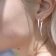 A model wears the Lucia earrings - made of pavé diamonds - which sparkle brilliantly in the sun. The twist earrings are delicate and seem to dance with movement. Earrings are sold as a pair, with complementary diamond / gold links. White Gold shown here. Reach out to our team for customization options.
